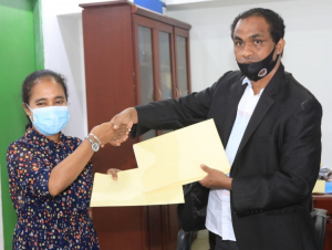 Diretór Jerál Kooperativa SEKOOP, Francisco Xavier, entrega hela nota ne’ebé asina ba Country Director Plan Internasional Timor-Leste, Dillyana Ximenes.